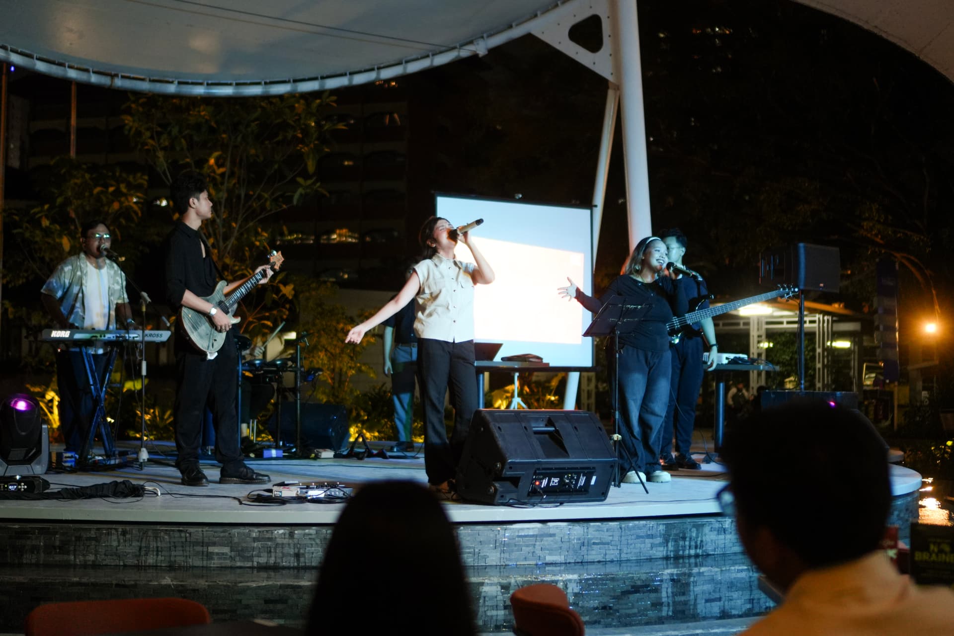 A band performing live on an outdoor stage at an ARC BARE showcase